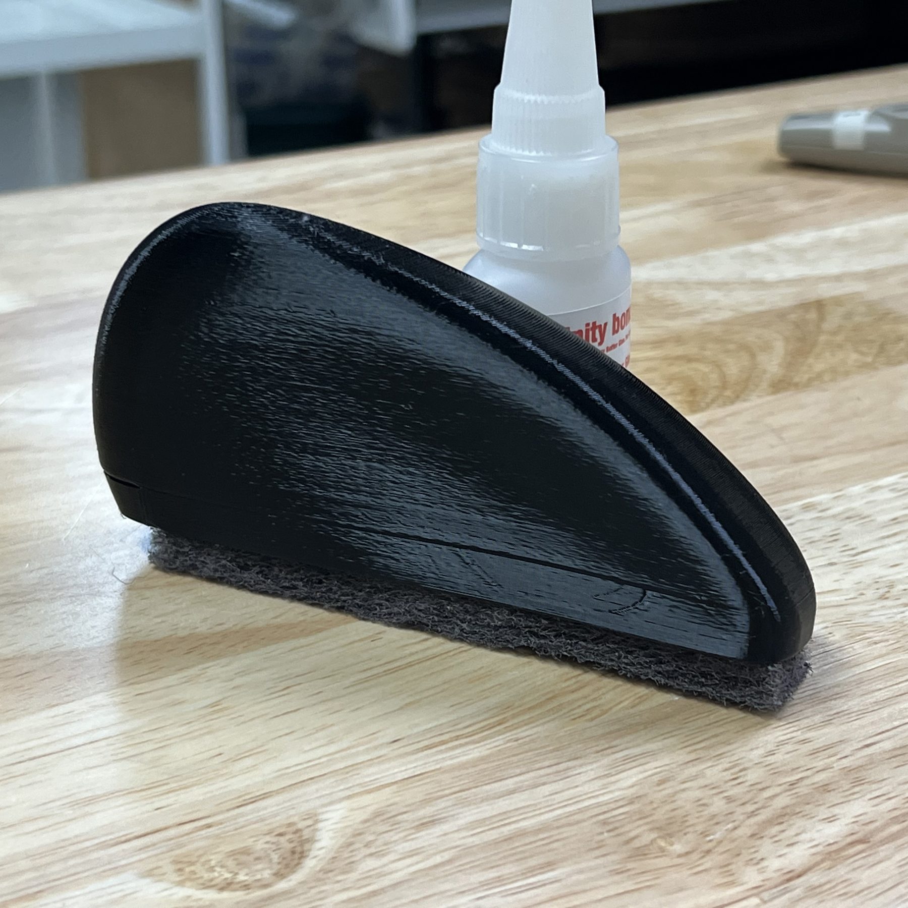 The finished brush resting on a workbench beside a bottle of adhesive