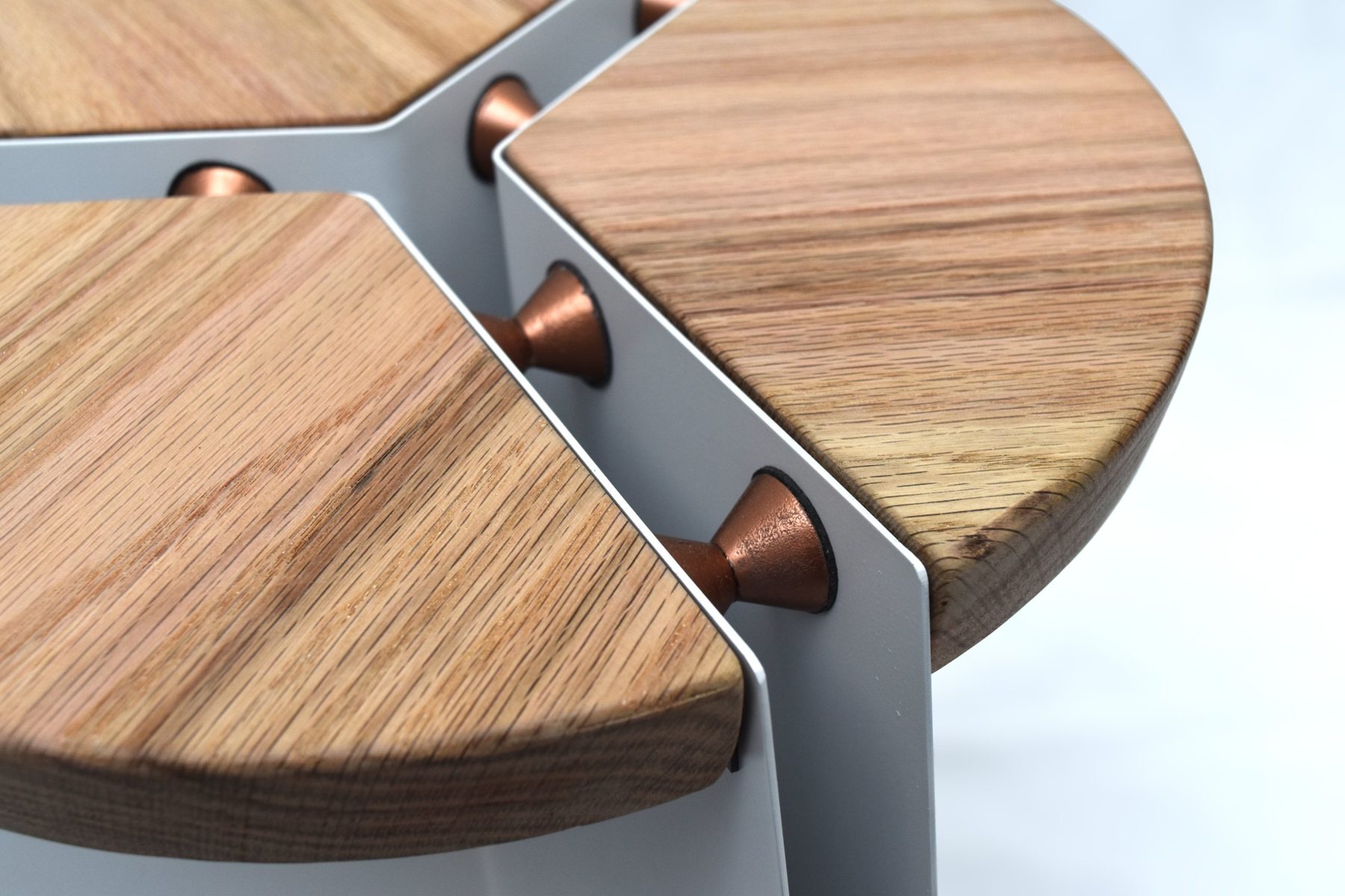 Copper spacers bridging the gap between the oak seat segments and the aluminum base