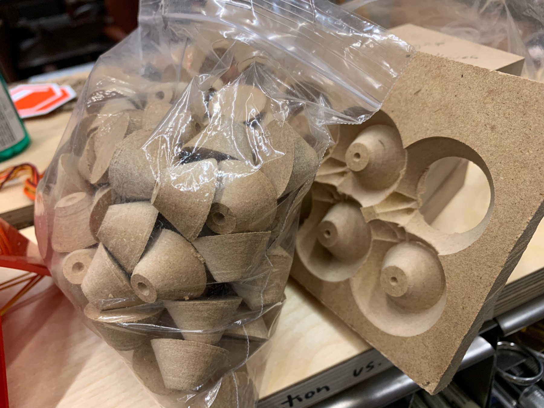 Bag of turned spacers beside the MDF fixture used to make them